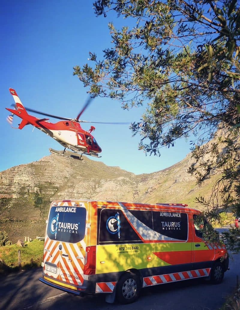 Rescue helicopter landing beside a Taurus ambulance on a mountain pass